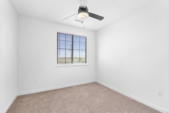 A room with a ceiling fan and a window with blinds.